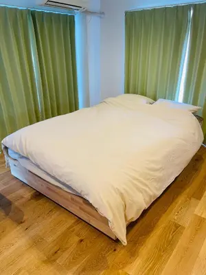 a bed with white sheets in a room with green curtains at home Shinjuku west302 in Tokyo