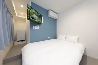 a bedroom with a white bed and a flat screen tv at IKEBUKURO MANGA HOUSE in Tokyo