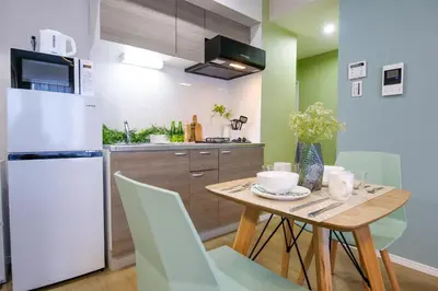 a kitchen with a wooden table and a white refrigerator at Premium Apartment Hotel Tokyo East in Tokyo