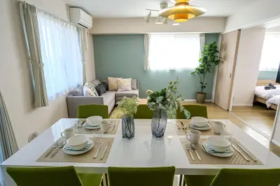 a dining room with a white table and green chairs at Premium Apartment Hotel Tokyo East in Tokyo