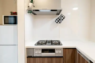 a kitchen with a stove and a white wall at Maison Novel under Skytree in Tokyo