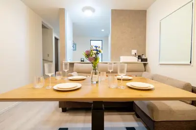 a dining room table with glasses and flowers on it at Maison Novel under Skytree in Tokyo