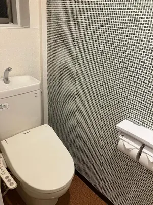 a bathroom with a white toilet and a tiled wall at Cube Stay \u5317\u6771\u4eac in Tokyo