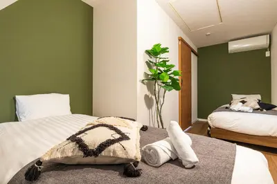 a bedroom with two beds with green walls at Pufuka Shin nakadori in Tokyo