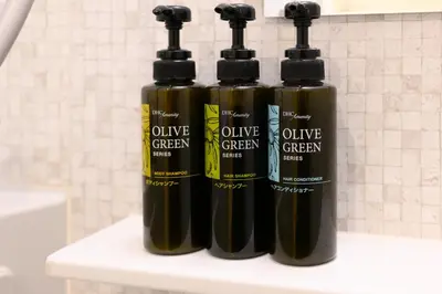 three bottles of olive green liquids sitting on a shelf at Rento Park Shiba 401 in Tokyo