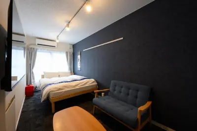 a bedroom with a bed and a couch and a chair at Rento Park Shiba 401 in Tokyo
