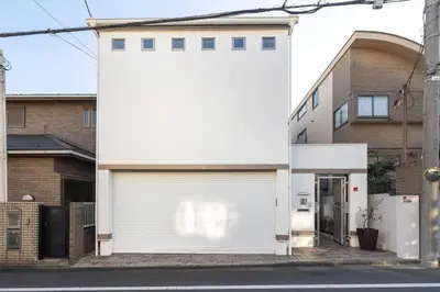 a white garage door on a white house at Okusawa Private House in Tokyo