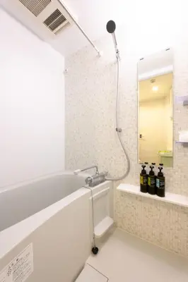 a bathroom with a bath tub and a mirror at Rento Park Shiba 501 in Tokyo