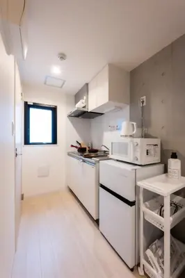 a small kitchen with white appliances and a table at Rento Park Shiba 501 in Tokyo