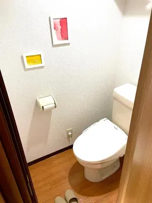 a bathroom with a toilet and some pictures on the wall at HARUKAZE HOUSE in Tokyo