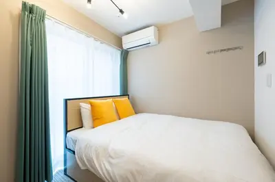 a bedroom with a bed with yellow pillows and a window at belle ville \u795e\u697d\u5742 in Tokyo