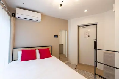 a bedroom with a white bed with red pillows at belle ville \u795e\u697d\u5742 in Tokyo