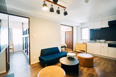 a living room with a blue couch and a table at BbyC APARTMENT 浅草花園通 レンタカー&サウナ付ホテル in Tokyo