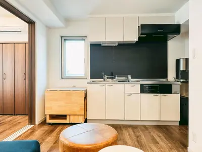 a kitchen with white cabinets and a wooden floor at BbyC APARTMENT 浅草花園通 レンタカー&サウナ付ホテル in Tokyo
