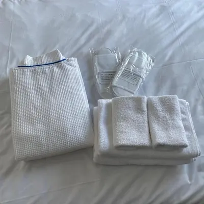two towels and a bag on a bed at BbyC APARTMENT 浅草花園通 レンタカー&サウナ付ホテル in Tokyo