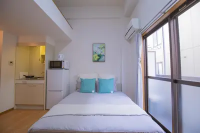 a bedroom with a bed with blue pillows and a window at Shinjuku Ryokan Retreat丶Local Tokyo Experience & Short Trips Hub丶walk to Higahsi Shinjuku station Y02f in Tokyo
