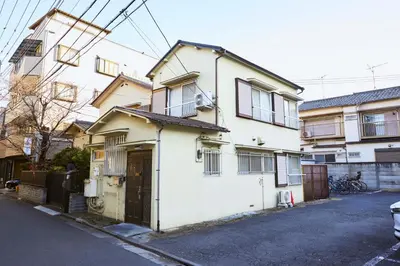 a white house on a street next to some buildings at Est house KAMEARI -Entire Tokyo House with Direct Bus Access to Airport and Disney in a Peaceful Local Neighborhood with 24 Hour Shops and Dining Options- in Tokyo
