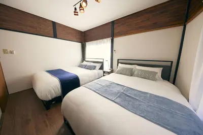 two beds in a small room with wooden walls at Est house KAMEARI -Entire Tokyo House with Direct Bus Access to Airport and Disney in a Peaceful Local Neighborhood with 24 Hour Shops and Dining Options- in Tokyo