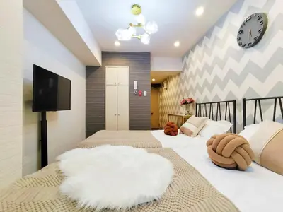 two beds in a bedroom with a tv on the wall at S15\u65b0\u5bbf\u6700\u4e2d\u5fc3 \u6771\u65b0\u5bbf\u7ad95\u5206-Shinjuku center 5 mins to Station, Max 3P \u65b0\u5bbf \u6d89\u8c37 \u8868\u53c2\u9053 \u6c60\u888b \u4e0a\u91ce \u4ee3\u4ee3\u6728 \u94f6\u5ea7 \u539f\u5bbf in Tokyo