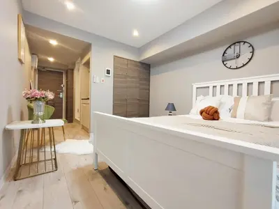 a large white bedroom with a large bed and a clock at S22\u65b0\u5bbf\u6700\u4e2d\u5fc3 \u6771\u65b0\u5bbf\u7ad95\u5206-Shinjuku center 5 mins to Station, Max 3P \u76f4\u8fbe\u76f4\u8fbe\u65b0\u5bbf \u6d89\u8c37 \u8868\u53c2\u9053 \u6c60\u888b \u4e0a\u91ce \u4ee3\u4ee3\u6728 \u94f6\u5ea7 \u539f\u5bbf in Tokyo