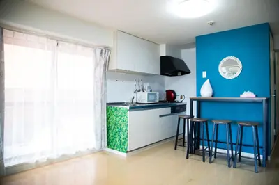 a kitchen with blue walls and stools and a counter at S19\u65b0\u5bbf\u6700\u4e2d\u5fc3 \u6771\u65b0\u5bbf\u7ad95\u5206-Shinjuku center 5 mins to Station, Max 6P \u76f4\u8fbe\u65b0\u5bbf \u6d89\u8c37 \u8868\u53c2\u9053 \u6c60\u888b \u4e0a\u91ce \u4ee3\u4ee3\u6728 \u94f6\u5ea7 \u539f\u5bbf in Tokyo