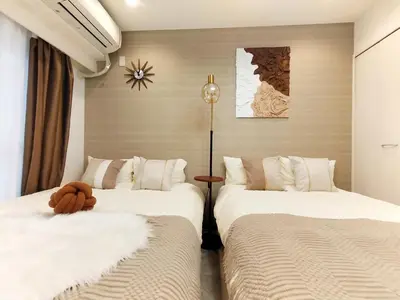 a bedroom with two beds and a clock on the wall at G53\u65b0\u5bbf\u6700\u4e2d\u5fc3 \u6771\u65b0\u5bbf\u7ad95\u5206-Shinjuku center 5 mins to Station, Max 4P \u76f4\u8fbe\u65b0\u5bbf \u6d89\u8c37 \u8868\u53c2\u9053 \u6c60\u888b \u4e0a\u91ce \u4ee3\u4ee3\u6728 \u94f6\u5ea7 \u539f\u5bbf in Tokyo