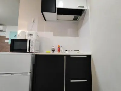 a kitchen with black cabinets and a white refrigerator at 43\u65b0\u5bbf\u6700\u4e2d\u5fc3 \u65b0\u5bbf\u5fa1\u82d1\u524d\u7ad95\u5206-Shinjuku center 5 mins to Station, Max 3 \u76f4\u8fbe\u65b0\u5bbf \u6d89\u8c37 \u8868\u53c2\u9053 \u6c60\u888b \u4e0a\u91ce \u4ee3\u4ee3\u6728 \u94f6\u5ea7 \u539f\u5bbf in Tokyo