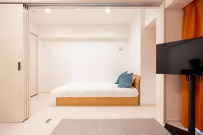 a bedroom with a bed and a flat screen tv at Noble Park KINSHICHO in Tokyo
