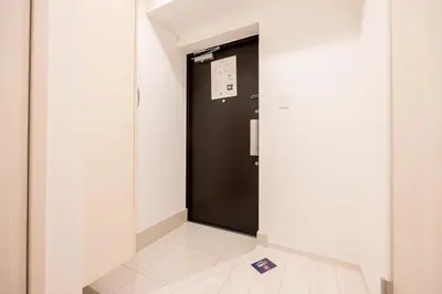 a hallway with a black door with a sign on it at Noble Park KINSHICHO in Tokyo