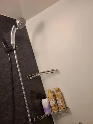 a shelf in a bathroom with a shower nozzle and bottles at 301\u53f7N\uff0b\u30db\u30c6\u30eb in Tokyo