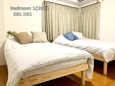 two beds in a room with white sheets and pillows at \u4e0a\u91ce\u685c\u6728 in Tokyo