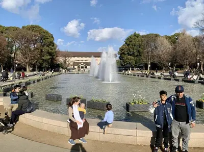 a group of people standing in front of a fountain at \u4e0a\u91ce\u685c\u6728 in Tokyo