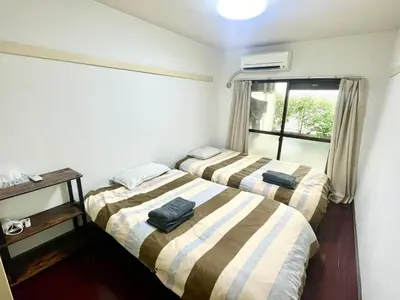 two beds in a small room with a window at Shibuya Honmachi Hana House in Tokyo