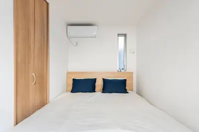 a bed with two blue pillows in a bedroom at Relastay Kamata in Tokyo