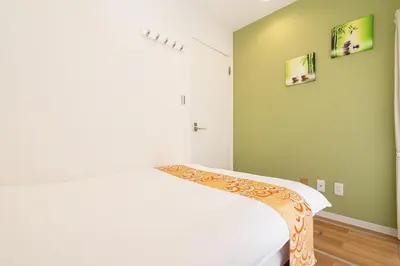 a bedroom with a white bed and green walls at KYARA Hotel\u30df\u30b9\u30df301 in Tokyo