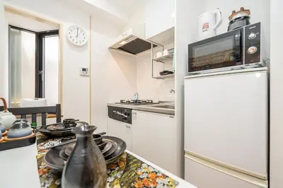 a kitchen with a refrigerator and a counter with dishes at KYARA Hotel\u30df\u30b9\u30df301 in Tokyo