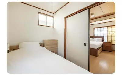 a bedroom with a white bed and a mirror at \u5c0f\u7af9\u306e\u5bbf\u65e5\u5f0f\u72ec\u680b\u4e09\u95f4\u5367\u5ba4\u6c60\u888b\u5730\u94c1\u4e94\u7ad9 in Tokyo