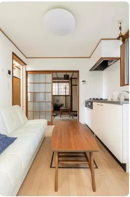 a living room with a white couch and a wooden table at \u5c0f\u7af9\u306e\u5bbf\u65e5\u5f0f\u72ec\u680b\u4e09\u95f4\u5367\u5ba4\u6c60\u888b\u5730\u94c1\u4e94\u7ad9 in Tokyo