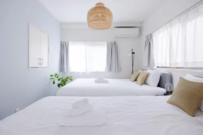 two beds in a bedroom with white walls and windows at Lido East Shinagawa\u3000 in Tokyo