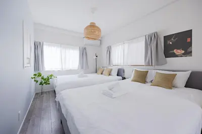 two beds in a room with white walls and windows at Lido East Shinagawa\u3000 in Tokyo