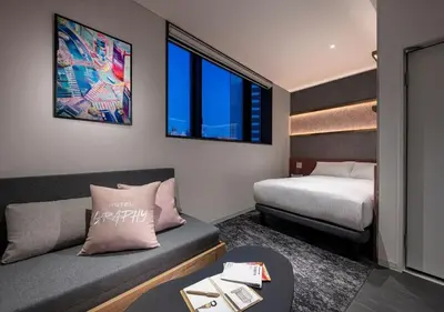 a small room with a bed and a couch and a table at HOTEL GRAPHY Shibuya in Tokyo