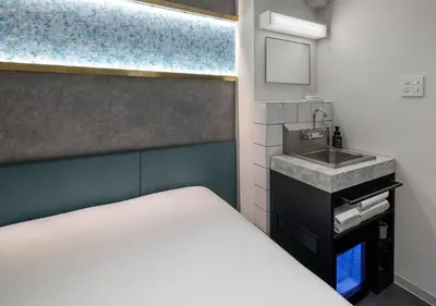 a small bedroom with a bed and a sink at HOTEL GRAPHY Shibuya in Tokyo