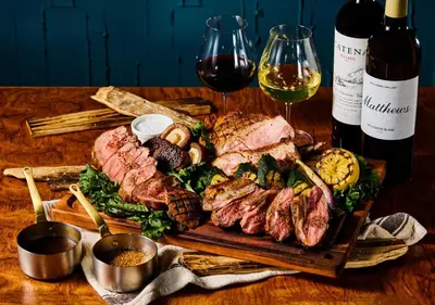 a table with a plate of meat and two glasses of wine at HOTEL GRAPHY Shibuya in Tokyo