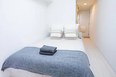 a white bed with a blue blanket on it at Shinjuku Serenity Studio-L06 in Tokyo