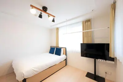 a bedroom with a bed and a flat screen tv at MAT SHIBUYAHONMACHI in Tokyo
