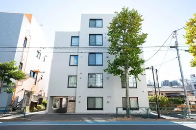 a white building with a tree in front of it at MAT SHIBUYAHONMACHI in Tokyo