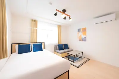 a white bedroom with a bed and a chair at MAT SHIBUYAHONMACHI in Tokyo
