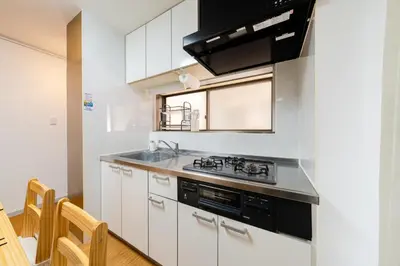 a kitchen with white cabinets and a stove top oven at SKY Building 201 - Easy Airport Access & Comfortable Stay in Tokyo