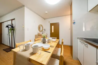 a dining room with a wooden table with white dishes on it at SKY Building 201 - Easy Airport Access & Comfortable Stay in Tokyo