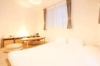 a bedroom with two beds and a table and a window at Mi-Villa Pure Gray in Tokyo